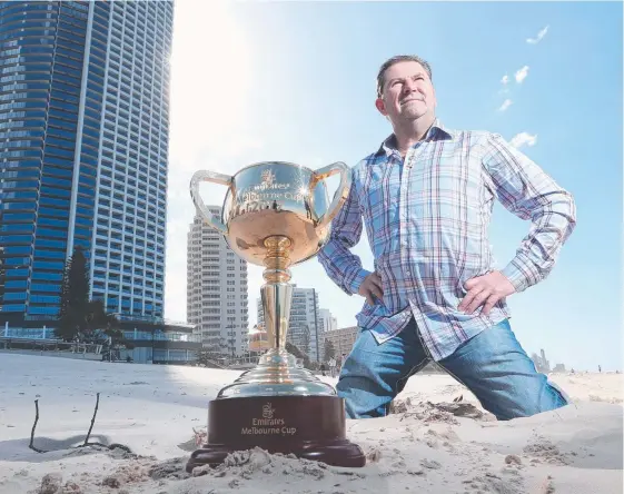  ?? Picture: GLENN HAMPSON ?? Former jockey Wayne Harris on Surfers Paradise beach yesterday with the Melbourne Cup. He rode Jeune to victory in 1994.