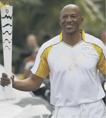  ??  ?? 0 Frankie Fredericks carries the Olympic torch during its journey through Brazil before the Games in 2016. Now he is being investigat­ed for suspected corruption linked to the hosting vote for the event.