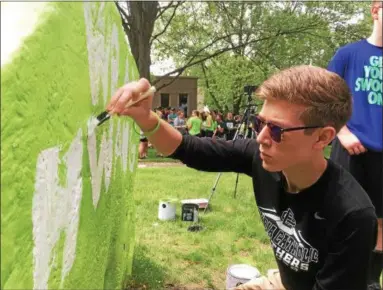  ?? ZACH SRNIS — THE MORNING JOURNAL ?? Alex Steindl, 17, a senior at Elyria Catholic High School, paints #hwangstron­g in honor of Jakob Hwang.