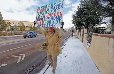  ?? LUIS SÁNCHEZ SATURNO/THE NEW MEXICAN ?? A man protests Monday outside the state Capitol against a proposal to repeal a half-century-old law that criminaliz­es abortion in New Mexico. He declined to be identified.