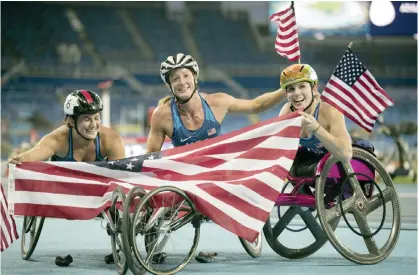  ??  ?? RIO DE JANEIRO: Tatyana McFadden, center, holds a flag as she won her third gold medal of the games, Chelsea McClammer, left, won the silver and Amanda McGrory won the bronze at the 2016 Paralympic Games in Rio de Janeiro, Brazil. — AP