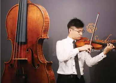  ?? PARKER ZHENG / CHINA DAILY ?? A musician plays a 1684 violin by Antonio Stradivari at Sotheby’s Hong Kong in Admiralty on Tuesday. The violin, which is estimated to be worth HK$12 million to HK$19 million, will be offered at Sotheby’s London on March 28.