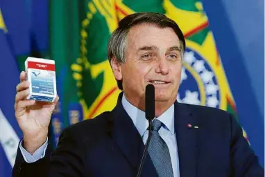  ?? Adriano Machado -16.set.20/Reuters ?? Bolsonaro segura caixa de cloroquina na cerimônia de posse de Eduardo Pazuello como ministro da Saúde, em setembro