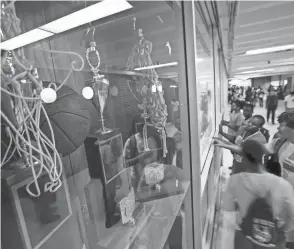  ?? EAMON QUEENEY/COLUMBUS DISPATCH FILE ?? Between classes, students check out their field day teams for the next day as OHSAA state championsh­ip trophies in boys basketball (2002), left, girls track and field (1998), center, and girls basketball (1996), right, sit in a case in the main hallway of Brookhaven High on May 15, in 2014.