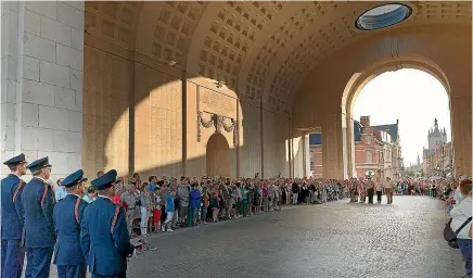  ??  ?? A remembranc­e service is held at the Menin Gate every day. Below, the Menin Gate lit up at night.