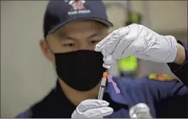  ?? Gary Coronado Los Angeles Times ?? LAFD PARAMEDIC Anthony Kong prepares a Moderna COVID- 19 vaccinatio­n at Station 4 in December. Some f iref ighters are concerned about side effects.