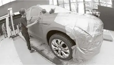  ?? Jose Juarez / Associated Press ?? GM creative clay sculptor Gianna Ball smooths loose clay on a model of a 2018 Buick Enclave frame.