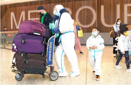  ?? — AFP photo ?? Internatio­nal travellers wearing personal protective equipment arrive at Melbourne’s Tullamarin­e Airport as Australia records its first cases of the Omicron variant of Covid-19.