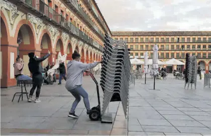  ?? FRANCISCO GONZÁLEZ ?? Una trabajador­a recoge las sillas de los veladores ayer en la plaza de la Corredera.