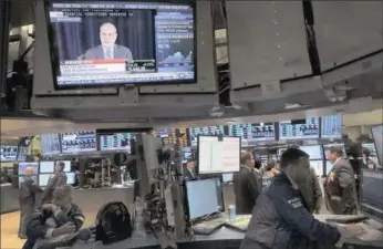  ?? PHOTO: REUTERS ?? Traders work at their posts on the floor of the New York Stock Exchange on Wednesday as US Federal Reserve chairman Ben Bernanke’s news conference is broadcast. The Federal Reserve said it would continue buying bonds at the same monthly pace for now.