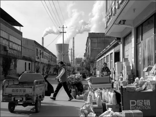  ?? NG HAN GUAN / ASSOCIATED PRESS ?? Guohua Power Station, a coal-fired power plant, operates Nov. 10 as people sell items on a street in Dingzhou, Baoding, in northern China’s Hebei province.