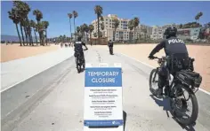  ??  ?? Police officers patrol along the closed and nearly empty Santa Monica beach Friday. LA County beaches reopened Monday.