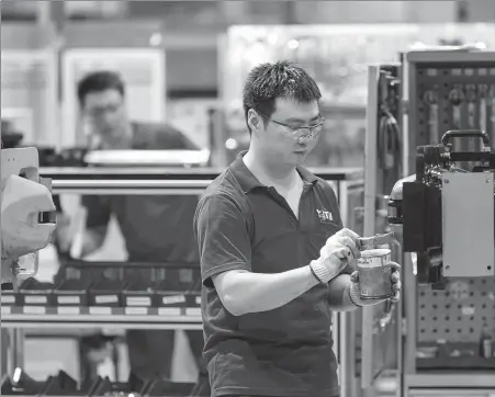  ?? WANG XIANG / XINHUA ?? Voith Turbo employees work at a production facility in Shanghai in July.