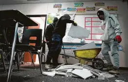  ?? Melissa Phillip / Staff photograph­er ?? Workers clean up damage Thursday in a classroom at Tomball Memorial High School caused by broken pipes in the fire suppressio­n system.