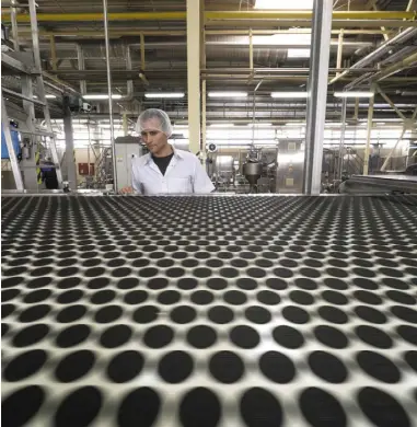  ??  ?? A worker performs quality control checks on Oreo biscuits on a factory production line