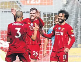  ??  ?? Team-mates Fabinho and Mo Salah celebrate with Andy Robertson