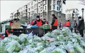  ?? TONG YU / FOR CHINA DAILY ?? Community workers distribute vegetables for quarantine­d residents in Tianjin’s Xiqing district on Wednesday.