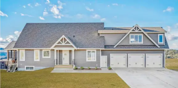  ??  ?? James Hardie plank and shingle siding provides a low maintenanc­e yet handsome exterior that enhances steep roof pitches clad in architectu­ral asphalt with truss details and cottage-style garage doors.