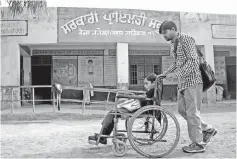  ??  ?? Disabled Indian school student Gurcharan Singh is pushed on her wheelchair towards school in the village of Teja Ruhela.