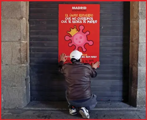  ??  ?? A man, wearing a protective mask, places a poster on the door of a closed shop due to the coronaviru­s outbreak in central Madrid, Spain