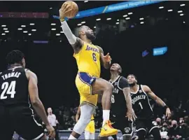  ?? Frank Franklin II Associated Press ?? THE LAKERS’ LeBron James drives past Brooklyn’s James Johnson (16) as Cam Thomas watches. James finished with 33 points in the Lakers’ 106-96 victory.