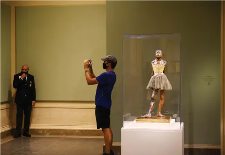  ?? — Photos by Washington Post ?? A visitor takes a photograph beside Edgar Degas’ famous ‘Little Dancer Aged Fourteen’ sculpture at the newly reopened National Gallery of Art in Washington, DC.
