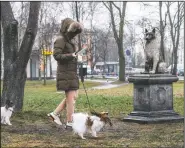  ??  ?? A woman walks with her dogs past the statue of Zorik.