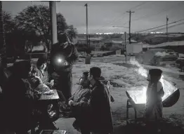  ?? Tamir Kalifa / New York Times ?? The Traugott family of Austin, left without power Feb. 17 in the winter storm, play Uno near a fire made from wood scavenged from a discarded armoire.