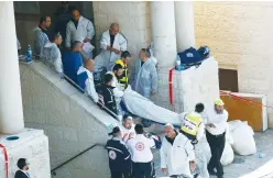  ?? (Ronen Zvulun/Reuters) ?? EMERGENCY PERSONNEL carry the body of a victim of the Har Nof synagogue terrorist attack in Jerusalem in 2014, carried out by the PFLP.