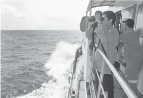  ?? HERI JUANDA/The Associated Press ?? A member of Indonesian National Search and Rescue Agency (BASARNAS) uses binoculars to scan the horizon during a search operation for the missing Malaysia Airlines Boeing 777.