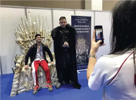  ??  ?? Sean Steven, 16, on a replica of the Westeros throne with Warren Eltringham, dressed as Jon Snow, at the Northern Irish stand of the Najah Abu Dhabi education fair. Left, pupils from Al Khazna School in Al Ain at the US stand Roberta Pennington and...
