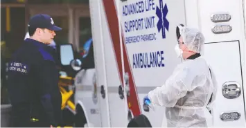  ?? — REUTERS FILES ?? A firefighte­r and a paramedic speak outside the Lynn Valley Care Centre in North Vancouver on March 9. The seniors' care home housed a man who was the first in Canada to die after contractin­g the coronaviru­s.