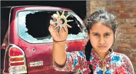  ?? NITIN KANOTRA/ HT ?? A girl displays a mortar shell fired from the Pakistan side, in Arnia sector, Jammu.