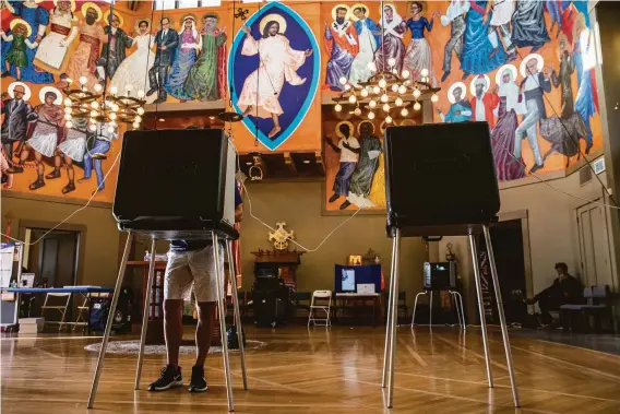  ?? Stephen Lam / The Chronicle ?? A voter casts a ballot in Tuesday’s election at a polling place inside St. Gregory’s Episcopal Church in San Francisco. Millions in the state voted early by mail.