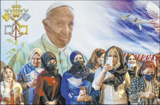  ?? Andrew Medichini The Associated Press ?? Women wait Saturday outside the Chaldean Cathedral of Saint Joseph in Baghdad as Pope Francis celebrates Mass.