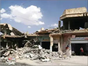  ?? SAFIN HAMED/AFP ?? An Iraqi man stands next to a damaged building in west Mosul on Thursday, a few days after the government’s announceme­nt of the ‘liberation’ of the embattled city from Islamic State group fighters.