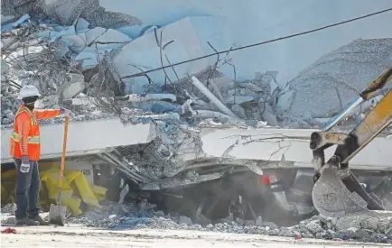  ?? Joe Raedle, Getty Images ?? A crushed vehicle is seen as law enforcemen­t and members of the National Transporta­tion Safety Board investigat­e Friday the scene where a pedestrian bridge collapsed a few days after it was built in Miami.