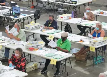  ?? MIKE BLAKE / REUTERS ?? Election workers look over some of the hundreds of thousands of early mail-in ballots as they are processed at the Orange County Registrar of Voters in Santa Ana, California, on Friday.