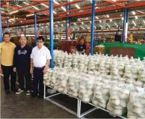  ??  ?? Fig. 2. The author (in white shirt) with friends in front of commercial­ly-processed Nam Hom and Nam Wan nuts at the auction market of Thailand.