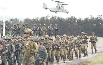  ?? AFP photo ?? File photo of Philippine and Australian soldiers marching in formation while a US marines V-22 Osprey hovers above during military exercise Alon (wave), a joint amphibious landing drill held at a naval base in San Antonio town in Zambales province, north of Manila. —