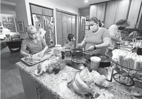  ?? KENNETH K. LAM / BALTIMORE SUN ?? Roslyn, left, and David Zinner, right, prepare dinner with Stephanie, center, and her son Samir, an asylum-seeking family from Honduras. The two families have been living together and sharing meals for almost two years.