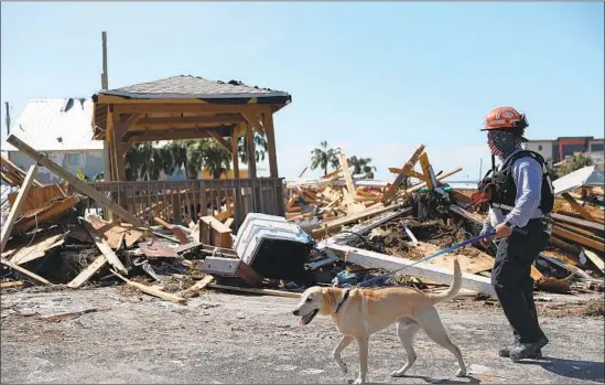  ?? Joe Raedle Getty Images ?? A SEARCH-AND-RESCUE TEAM looks for survivors amid the rubble left by Hurricane Michael in Mexico Beach, Fla. The storm hit with Category 4 winds.