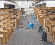  ?? (AP/Hiro Komae) ?? Constructi­on workers fold a tarp sheet at a closed building complex being built as part of the athletes’ village to be used during the postponed Olympic and Paralympic Games in Tokyo.