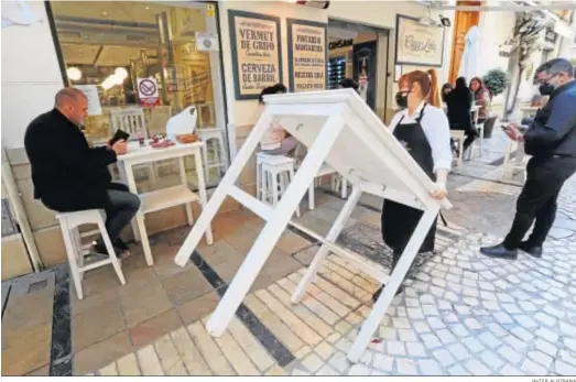  ?? JAVIER ALBIÑANA ?? Una camarera coloca una mesa en el exterior de un bar de Málaga.