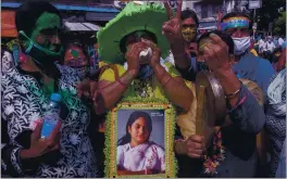  ?? ASHIM PAUL — THE ASSOCIATED PRESS ?? Supporters of Trinamool Congress party chief Mamata Banerjee holding an earlier photograph of her celebrate an early lead for the party in the West Bengal state elections in Kolkata, India, Sunday.