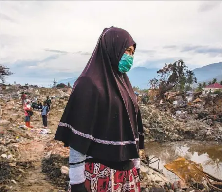  ?? Ulet Ifansasti Getty Images ?? A WOMAN waits for news of her two missing daughters in quake-damaged Balaroa, Indonesia, as rescuers search for buried victims. About 10,000 workers will conclude the official search on Friday. The government said the official death toll was 2,073 as of Thursday.