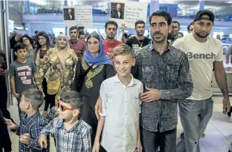  ?? DAVID LIPNOWSKI/THE CANADIAN PRESS ?? 12-year-old Emad Mishko Tamo, centre, stands with uncle Hadji Tamo and his mother Nofa Mihlo Rafo as he’s reunited with friends and family at Winnipeg’s James Armstrong Richardson Internatio­nal Airport, early Thursday. Emad Mishko Tamo was rescued by...