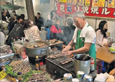  ?? / WIKEMEDIA ?? Un cocinero prepara comida en el mercado de Shibuya, en Tokio.
