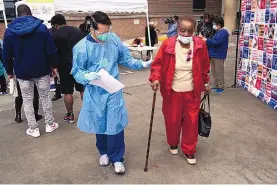  ?? JAE C. HONG/ASSOCIATED PRESS ?? Vera Eskridge, 86, right, is escorted into the waiting area by RN Angelo Bautista after getting her COVID-19 vaccine at a site in the parking lot of the Los Angeles Mission.