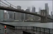  ?? CRAIG RUTTLE — THE ASSOCIATED PRESS ?? A runner moves along the Brooklyn shoreline of the East River as rain and clouds loom over lower Manhattan on the fifth anniversar­y of Superstorm Sandy Sunday in New York.